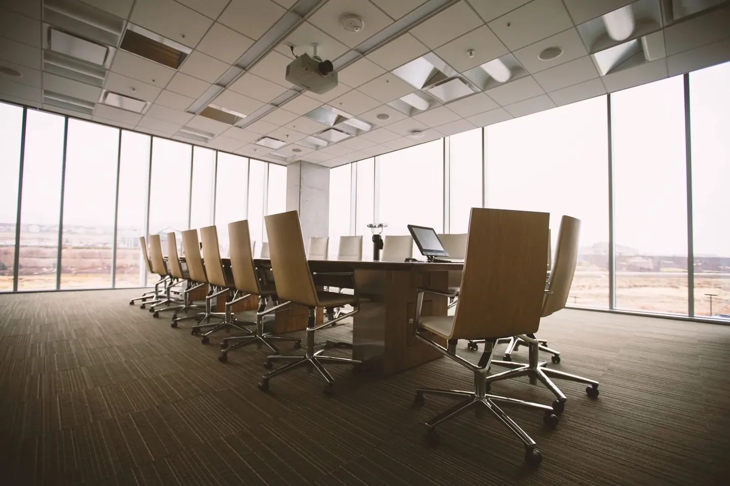Long boardroom table and office chairs beside floor-to-ceiling windows