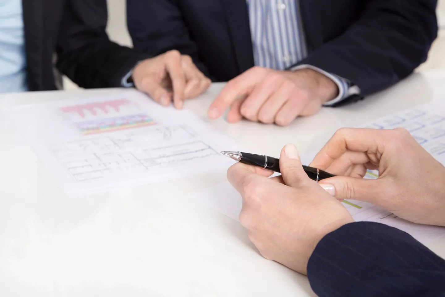 Advisers reviewing printed financial documents at a white table